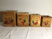 Front view of four vintage wooden kitchen containers labeled Flour, Sugar, Coffee, Tea with colorful painted bird designs.