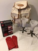 Front view of the entire lot showing the canvas backpack, Bally exercise ball box, tabletop lamps, and red leather gloves on display.
