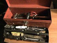 Photo of red metal Waterloo toolbox open showing tray with hand tools inside including wrenches and a mallet