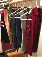 Photo of all hanging items: sweaters, skirts, jeans, tank tops, dress visible on hangers