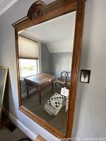 Full view of mirror leaning against wall, showing shape, frame, and size