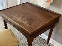 Side angle showing the full antique wooden desk with worn finish and turned legs.