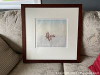 Framed print featuring a vintage biplane flying above clouds with a wooden frame and glass front.