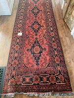 Full-length view of runner rug on wood floor showing overall pattern, border design, and condition of pile.