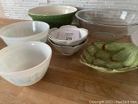 Photo of assorted mixing, baking, and serving bowls displayed on wooden countertop showing size and style variety