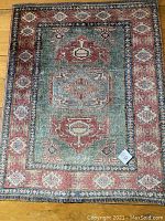 Full view of the rectangular area rug laid flat on floor showing central medallions, border and fringes