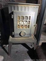 Front view of cast iron wood stove on 9" legs showing hexagonal glass window, latch and Coalbrookdale nameplate