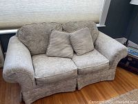 Light grey patterned loveseat with four cushions including two beige striped cushions