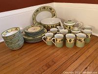 Full set arranged on floor including plates, bowls, mugs, teapot, creamer, sugar bowl, large platter, and serving bowl.