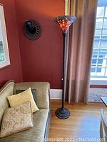 Full view of the floor lamp standing next to a sofa and window, showing height and base design.