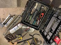 Photo of various hand tools including 3 hand saws, a metal spirit level, caulking gun, fire extinguisher, circular saw blade, and other miscellaneous tools.