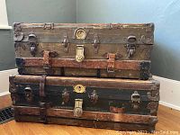 Stacked trunks showing metal clasps, leather straps, and wood panels on exterior.