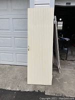 Full view of painted pine door standing upright outside garage