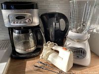 Full view of the coffee maker, tea kettle, blender, and handheld mixer on counter.