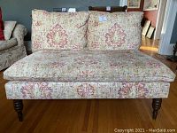 Frontal view of the two-person sofa with floral patterned upholstery, showing cushions and base detail.