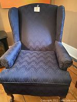 Front view of blue wingback accent chair showing upholstery and padding condition.