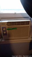 White Gree window air conditioner unit mounted in window, front view showing controls and vents.