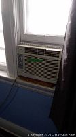 Photo of a white Gree window air conditioner unit installed in a window with two control dials and front air vents.