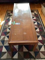 Top view of a rectangular wooden coffee table showing wear on surface and edges.
