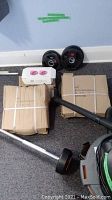 Overview of two tri-grip plates, cardboard packaging, dumbbell bar components and pink ankle weights box