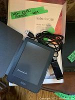 Kobo Clara HD reader powered off shown with USB cable and custom case inside original box with Quick Start Guide.