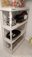 Plastic shelving unit in basement corner with various kitchen appliances on shelves (contents not included).