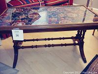 Full view of 1930s wooden coffee table with clear glass top showing floral petit point embroidery beneath.