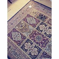 Area rug showing detailed grid pattern of multiple floral medallions in burgundy, beige, navy blue, black, and cream colors with decorative border.