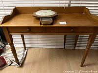 Maple antique two drawer desk with turned legs placed against a window with blinds. Two drawers with wooden knobs. Good used condition.