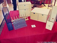 Photo showing five assorted desktop organizers on a red cloth-covered table including wooden and metal materials.