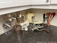 Photo of the corner kitchen counter showing all items including Cuisinart food processor, hand mixer, meat grinder, fruit juicer, and kitchen utensils