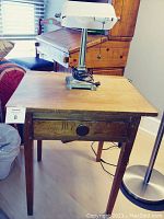 Photo of one pine Empire style end table with large round wooden knob drawer and banker style replica lamp on top.