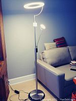Full view of floor lamp showing large circular LED main light and smaller adjustable LED light on a separate arm.