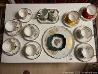 Overhead photo showing all cups, saucers, plates, sugar and cream servers arranged on white surface