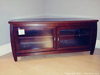 Full front view of the wood TV console stand showing the glass doors and dark wood finish.