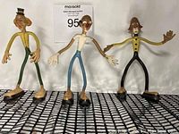 Three bendable clown figurines posed standing on a grid surface.