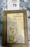 Front cover of the antique book showing the title 'The Cuckoo Clock' and illustration of a girl with flowers