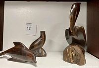 Photo showing all three wood animal figurines including dolphin, seal, and large bird on a white surface