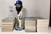Photo showing Brian Wilson Dodgers bobblehead centered between three large stacks of vintage baseball trading cards