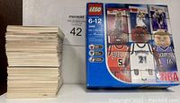 Stack of assorted NBA trading cards next to LEGO NBA Collectors box