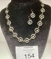 The full set displayed on black velvet bust showing the necklace and earrings together, including auction tag.