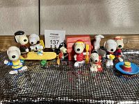 Full view of all 10 vintage Snoopy PVC figures arranged on black mesh fabric, showing various costumes and activities.