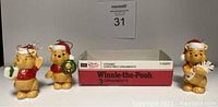 Three ceramic Winnie-the-Pooh Christmas ornaments displayed next to half of original Sears box. Each ornament wears a Christmas outfit and hat, holding different Christmas props.