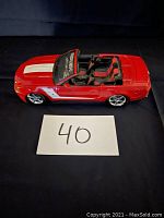 Red 2010 Ford Roush Mustang diecast model car with white stripes and black interior shown from front angle.