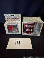 Photo showing both the red Antique Mail Truck model in its packaging and the boxed postal game mug side by side on a black background with lot number 14.