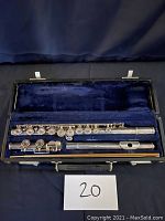 Silver flute disassembled and laid inside original blue-lined black case with Artley branding