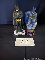 Front view of Batman Return ceramic piggy bank and Batman bubble bath bottle, both standing against dark blue background with lot number card in front.