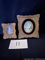 Two gold-tone ornate picture frames with portraits of women, black background, labeled with number 11