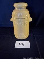 Front view of mustard yellow ceramic cookie jar showing embossed word 'COOKIES' and curved handles on both sides.