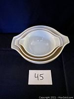 Top view of three nested white Pyrex mixing bowls with handles and pouring spouts.
